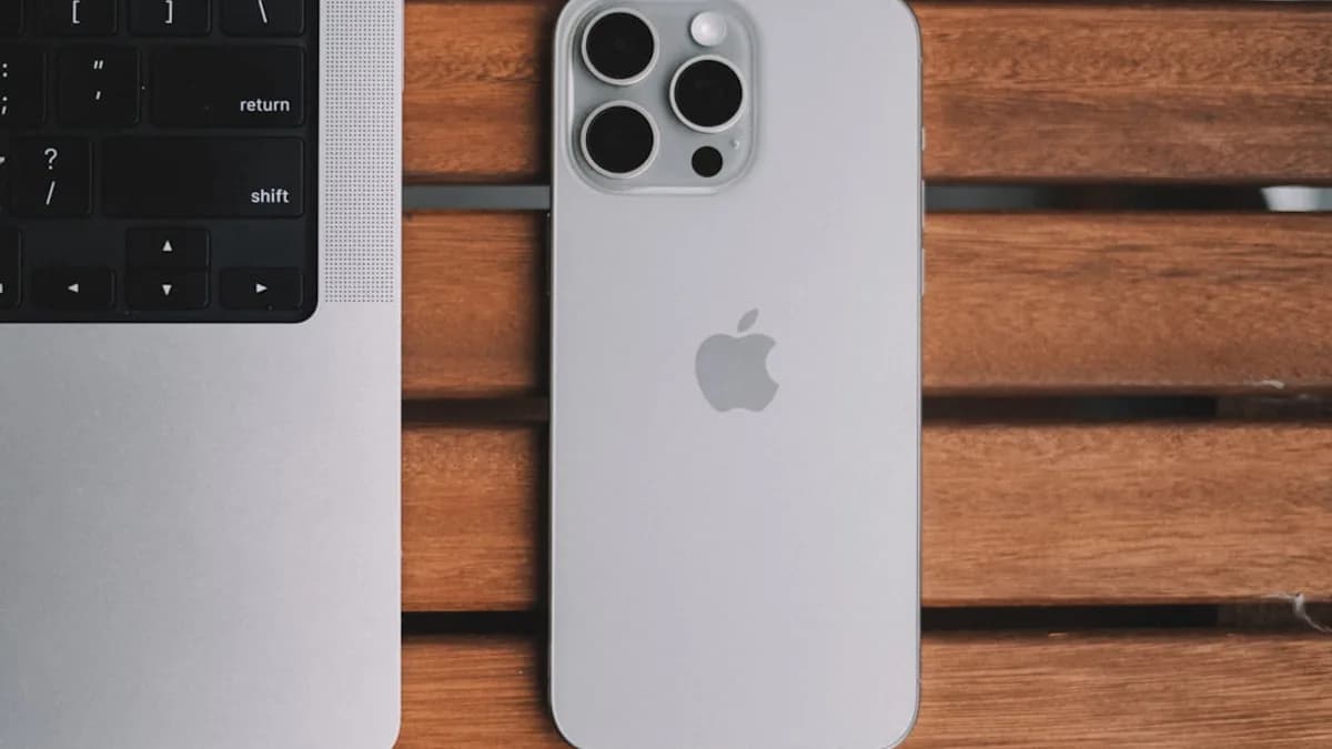 An iPhone and a laptop on a wooden table