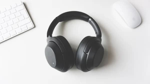 black wireless headphones between Apple Keyboard and Apple Magic Mouse on white surface