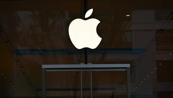 the apple logo is reflected in the glass of a building