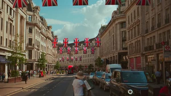 Union jack flags adorn a london street with people.
