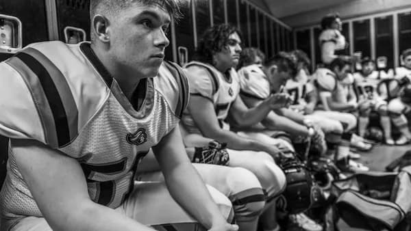 Football players sitting in a locker room