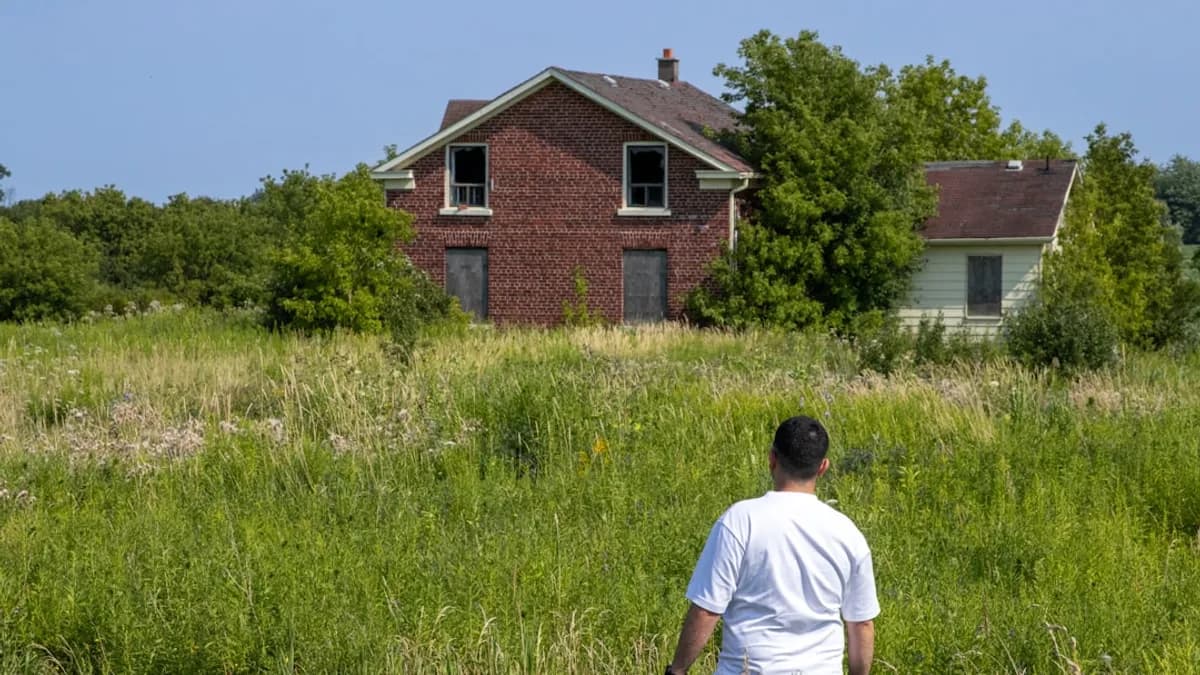 A man standing in a field next to a house