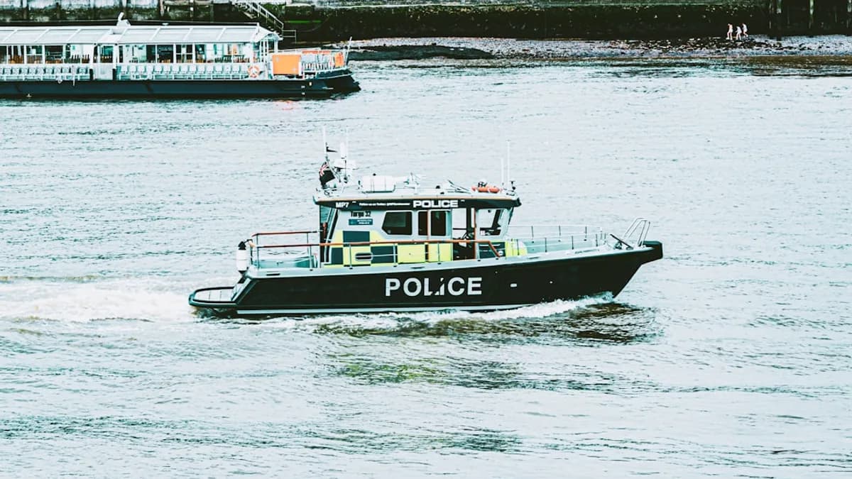a police boat traveling down a river next to a dock