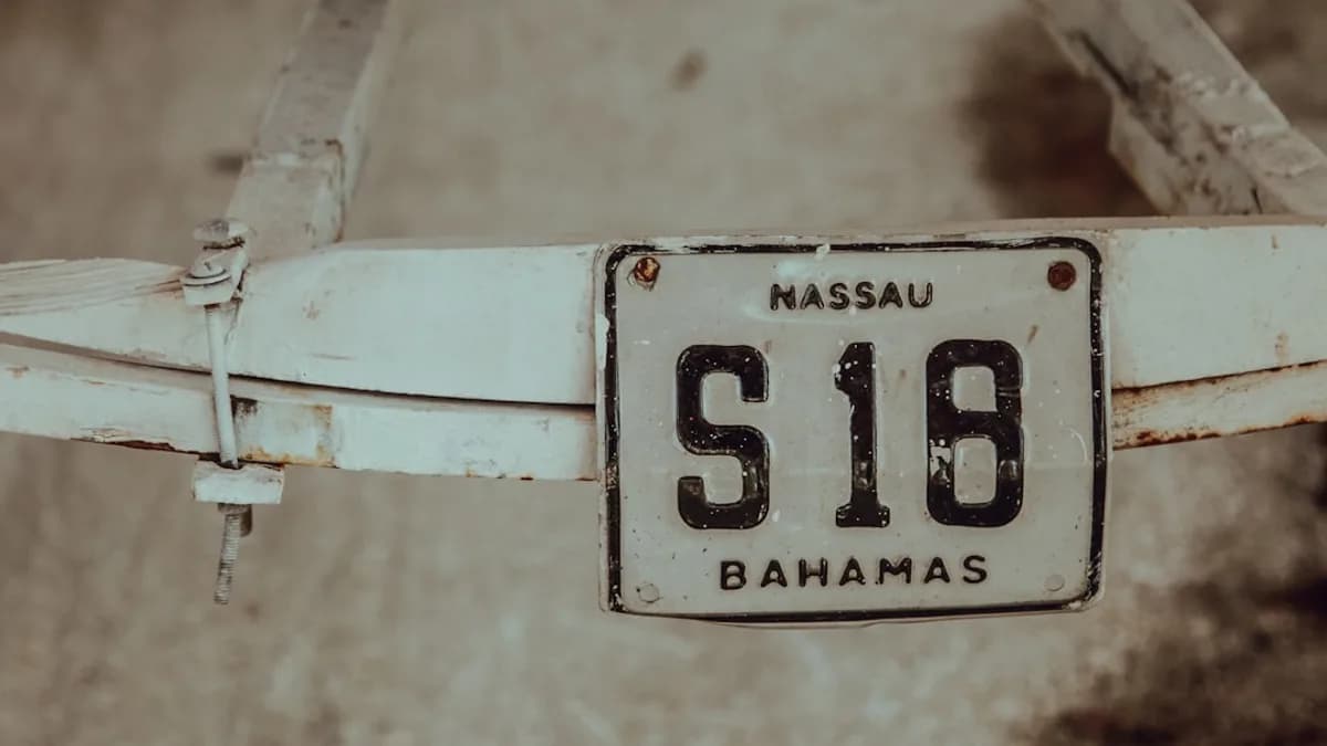 shallow focus photography of white Massau S18 Bahamas license plate mounted on white steel frame