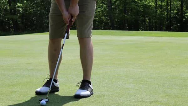 man in brown shorts and black nike shoes playing golf during daytime