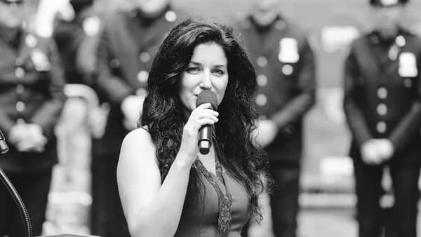 Woman speaking into microphone with police officers behind her