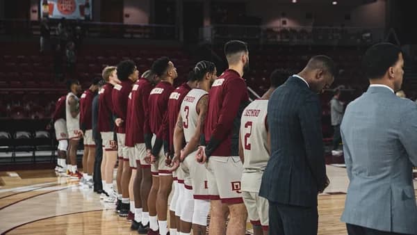 man in black suit jacket standing beside woman in red and white jersey shirt