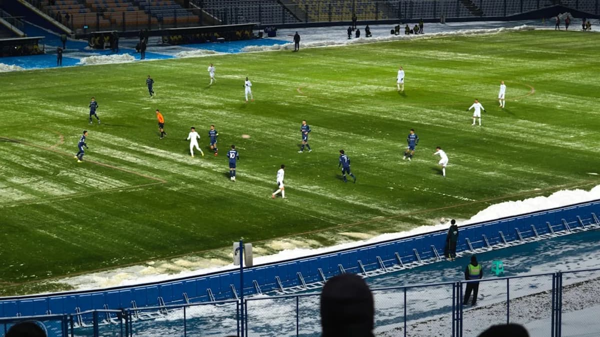 Soccer players on a snowy field during a game.