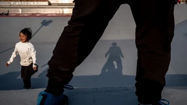 a young child standing on a skateboard at a skate park