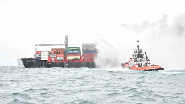 a tug boat spraying water on a large ship