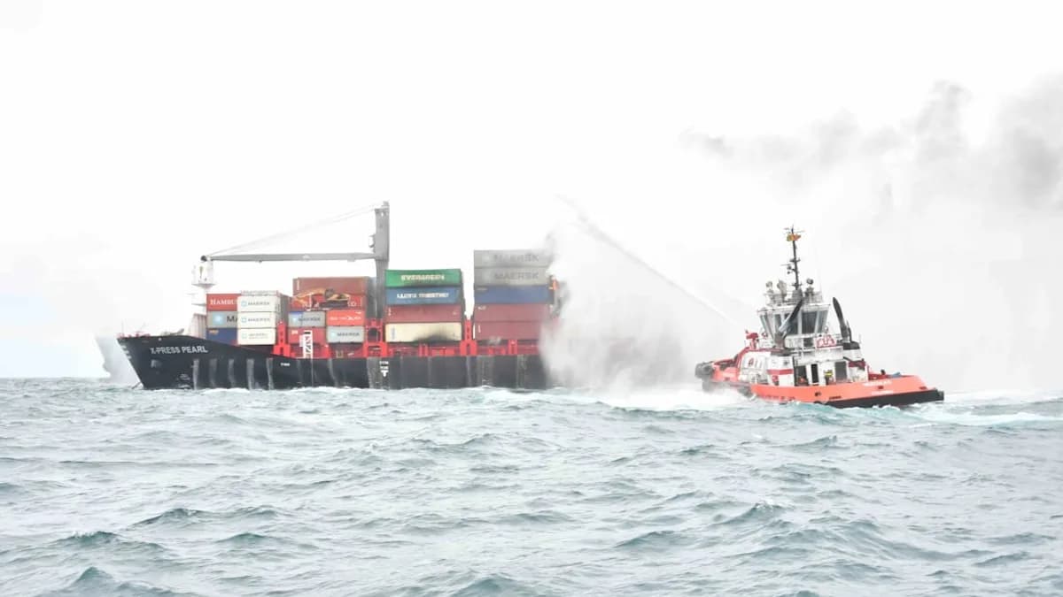 a tug boat spraying water on a large ship