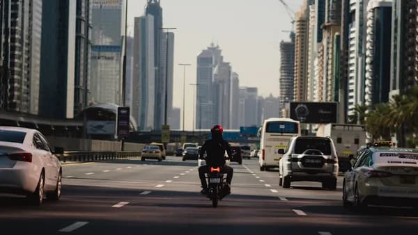 a man riding a motorcycle down a street next to tall buildings