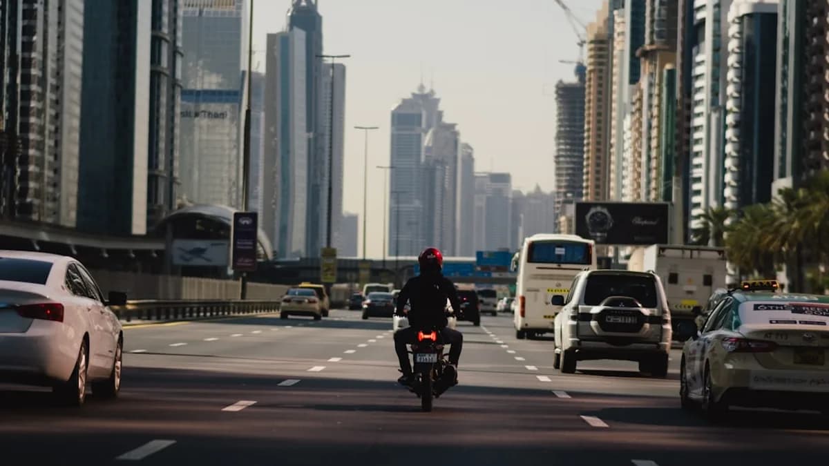 a man riding a motorcycle down a street next to tall buildings