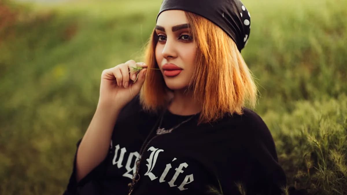 a person with a black hat and black shirt holding a cigarette