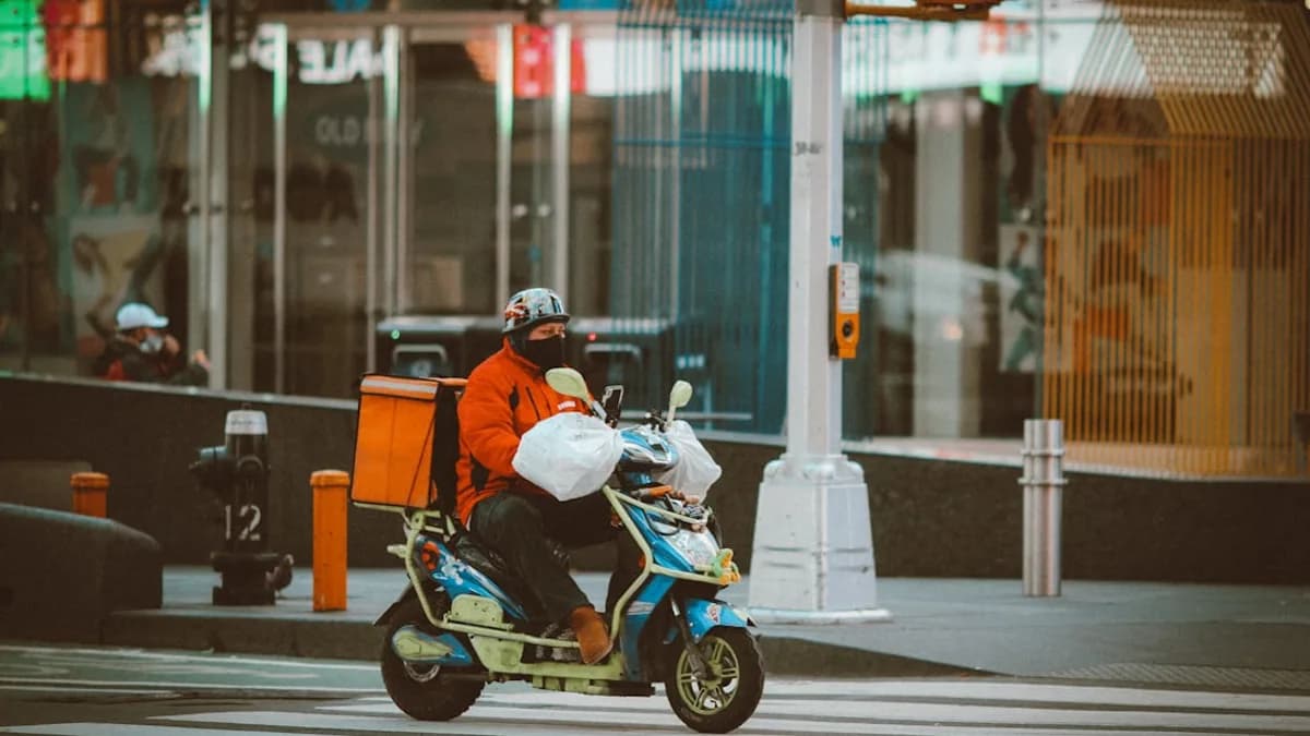 man in orange jacket riding on black and white motorcycle