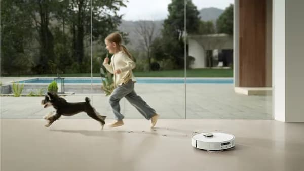 Girl and dog run past robot vacuum cleaner