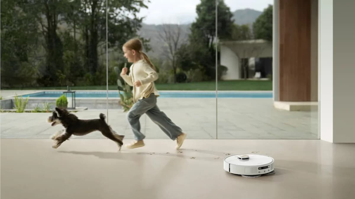 Girl and dog run past robot vacuum cleaner