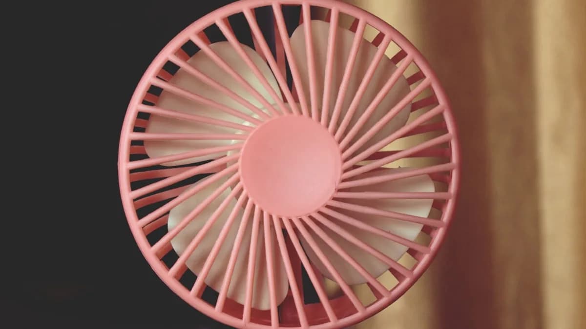 A pink fan sitting on top of a table
