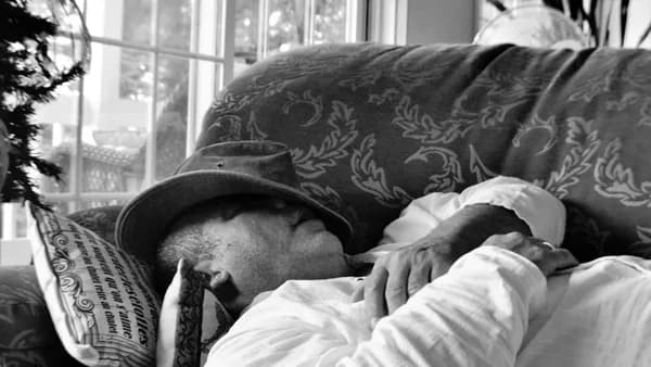 a man sitting on a couch wearing a hat