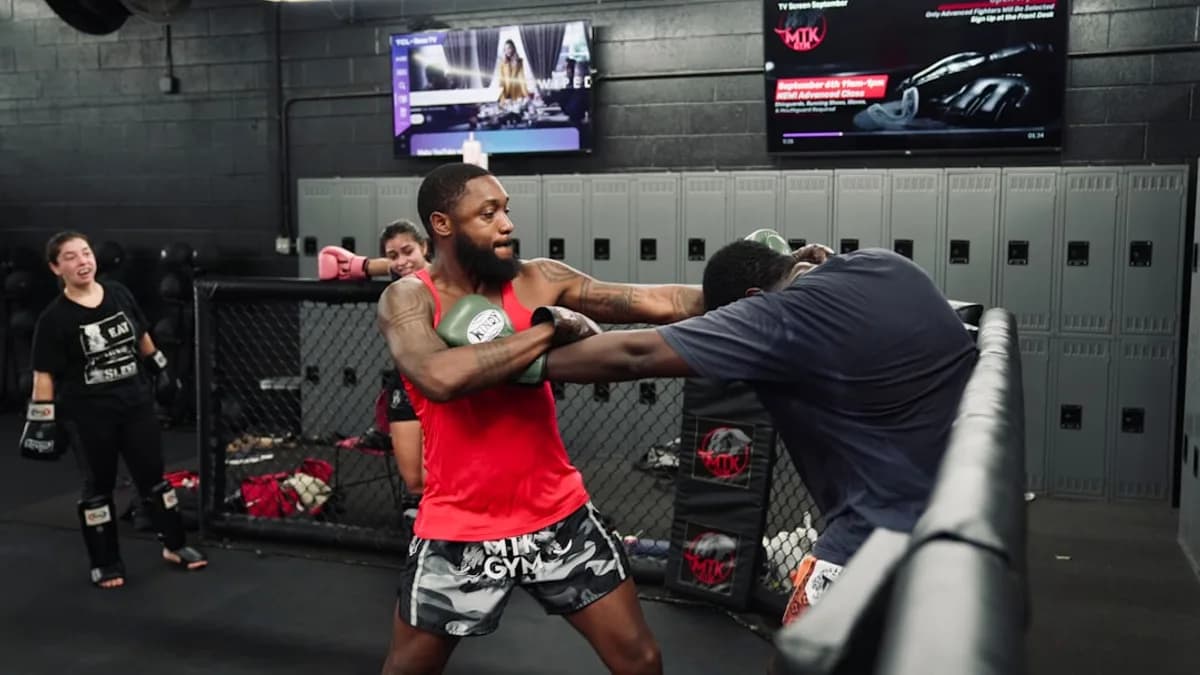 Two men sparring in a boxing gym with spectators.