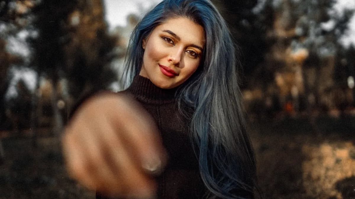 a woman with blue hair pointing at the camera