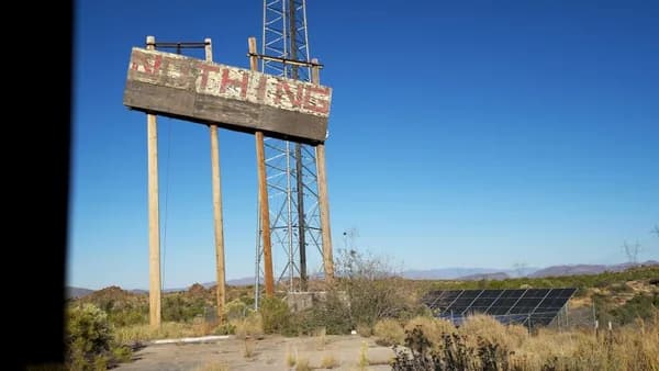 Abandoned sign reads "nothing" in a desert landscape.