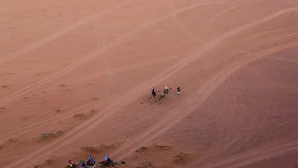 a group of people riding camels across a desert