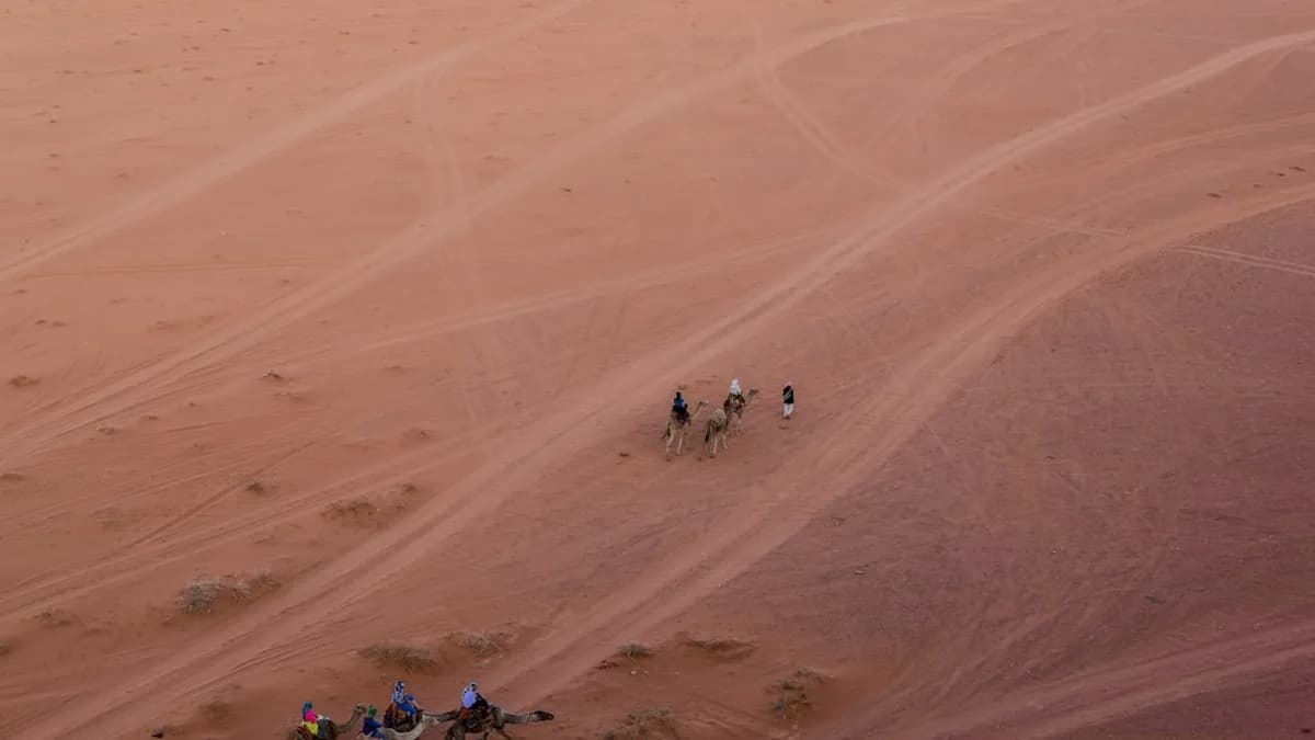 a group of people riding camels across a desert