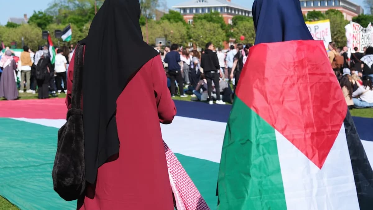 two women in burkas are walking in front of a large group of people