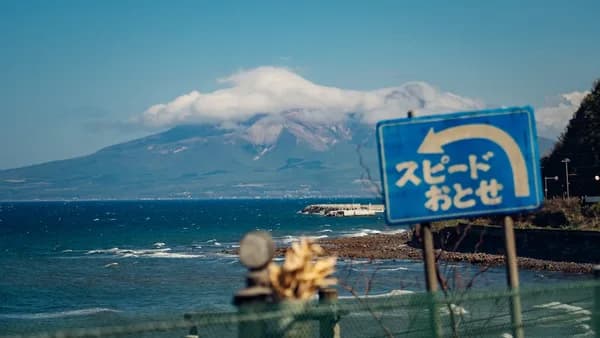 a blue sign sitting on the side of a road next to the ocean