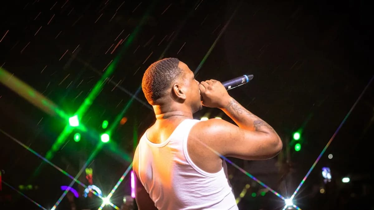a man in a white tank top singing into a microphone