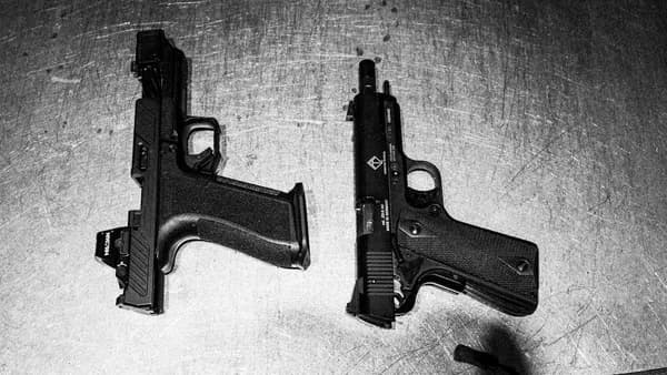 Two handguns are shown on a surface.