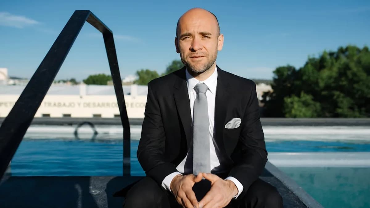 a man in a suit and tie sitting in front of a pool