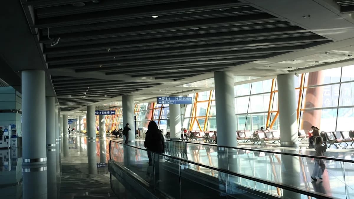 Traveler on a moving walkway in a modern airport terminal.