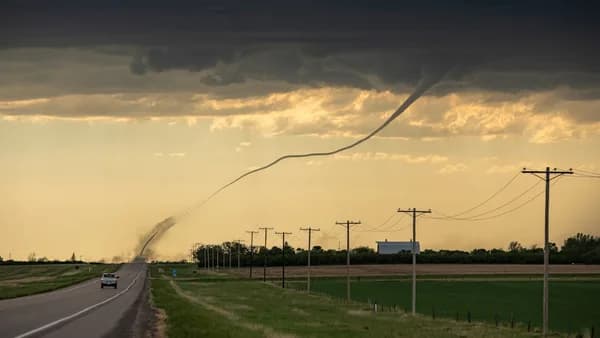 a car driving down a road under a cloudy sky