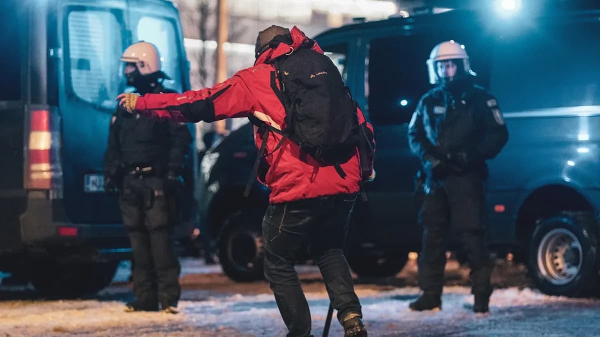 a man in a red jacket kicking a soccer ball