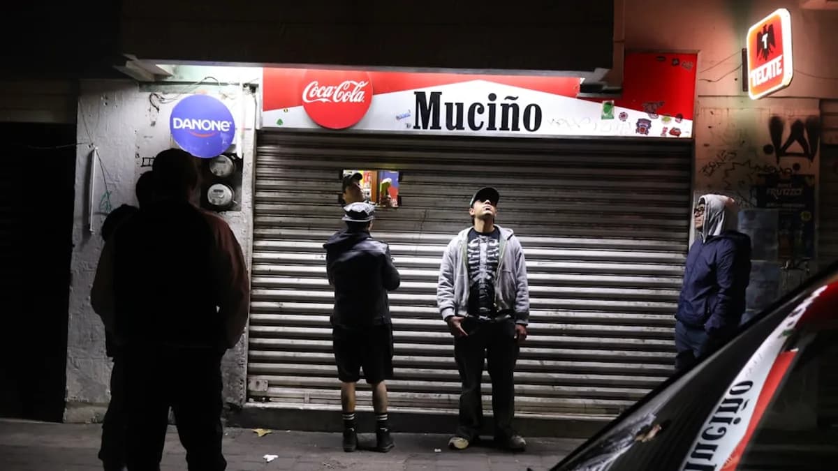 People stand outside a closed store at night.