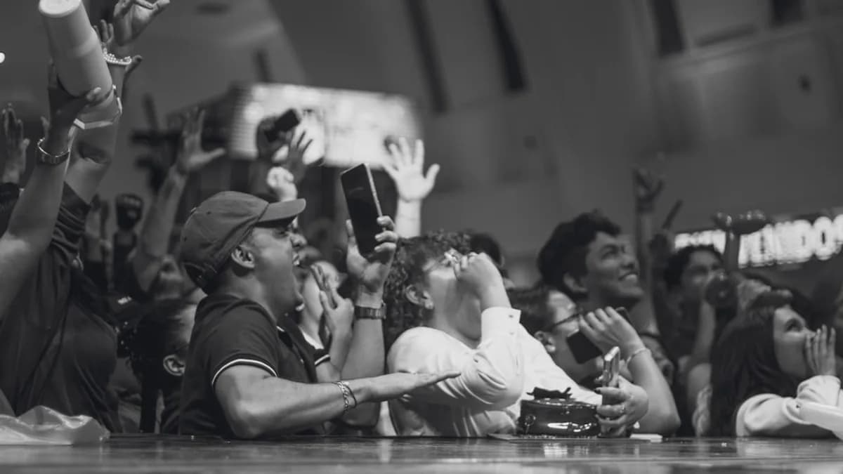 Crowd cheering and celebrating with arms raised.