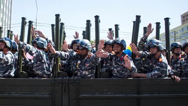 soldiers in brown and black camouflage uniform sitting on black metal frame during daytime