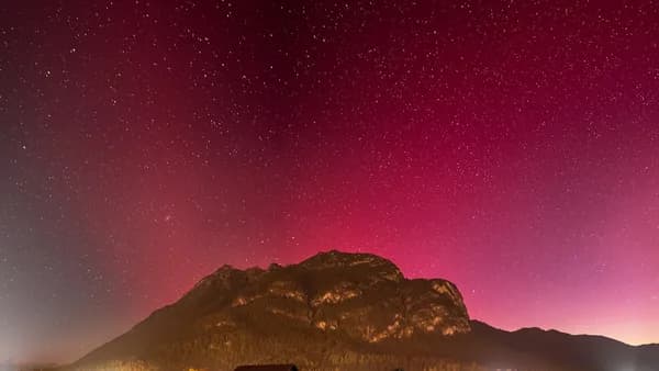 a field with a mountain in the background and stars in the sky