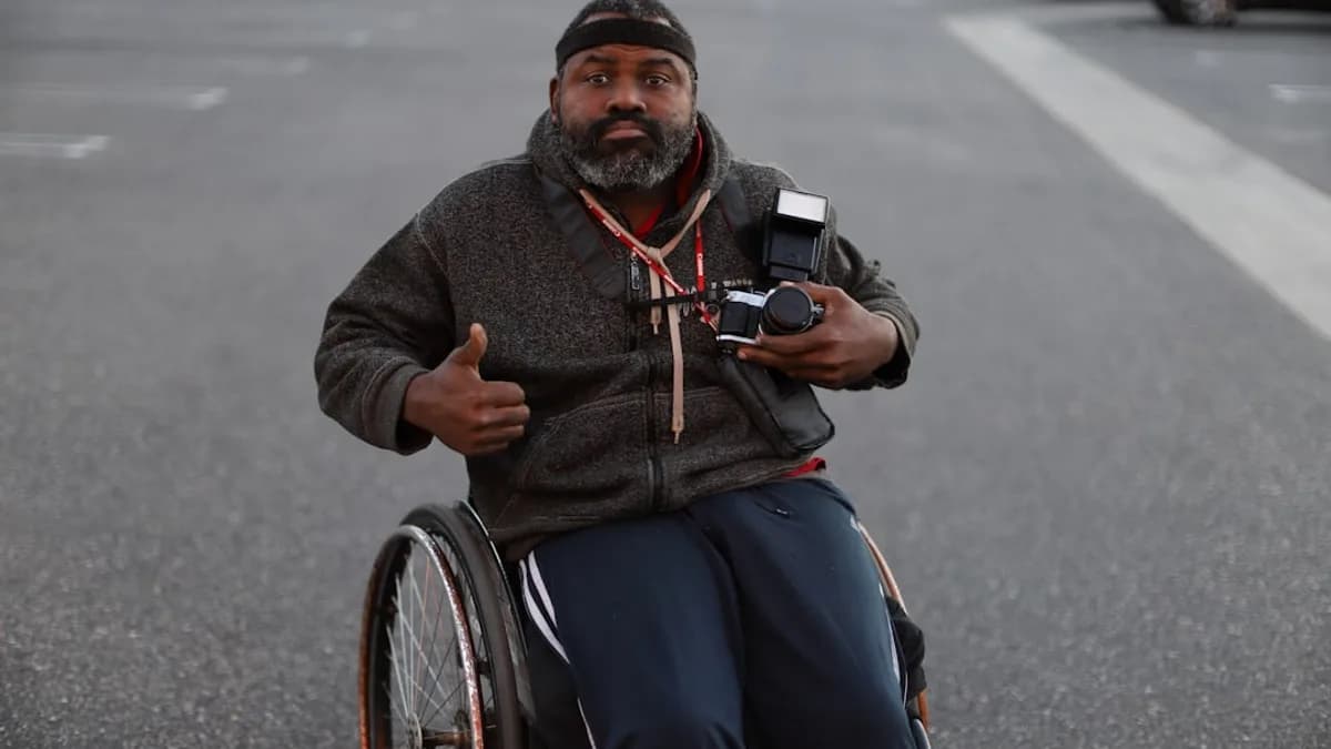 a man in a wheelchair pointing a camera