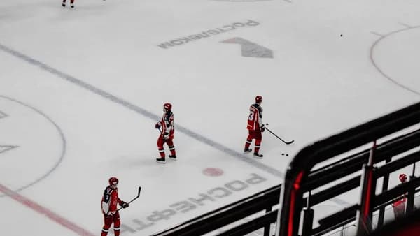 3 men in red suits walking on white snow during daytime