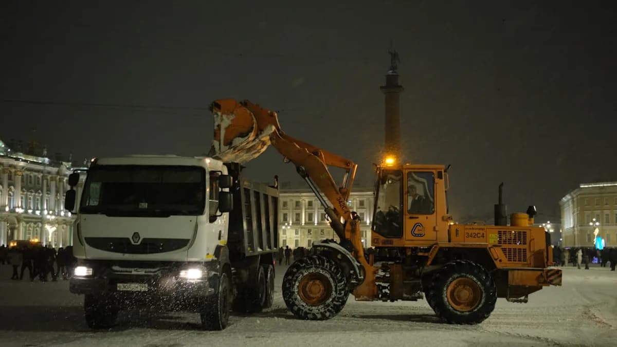 Loader dumping snow into a truck at night