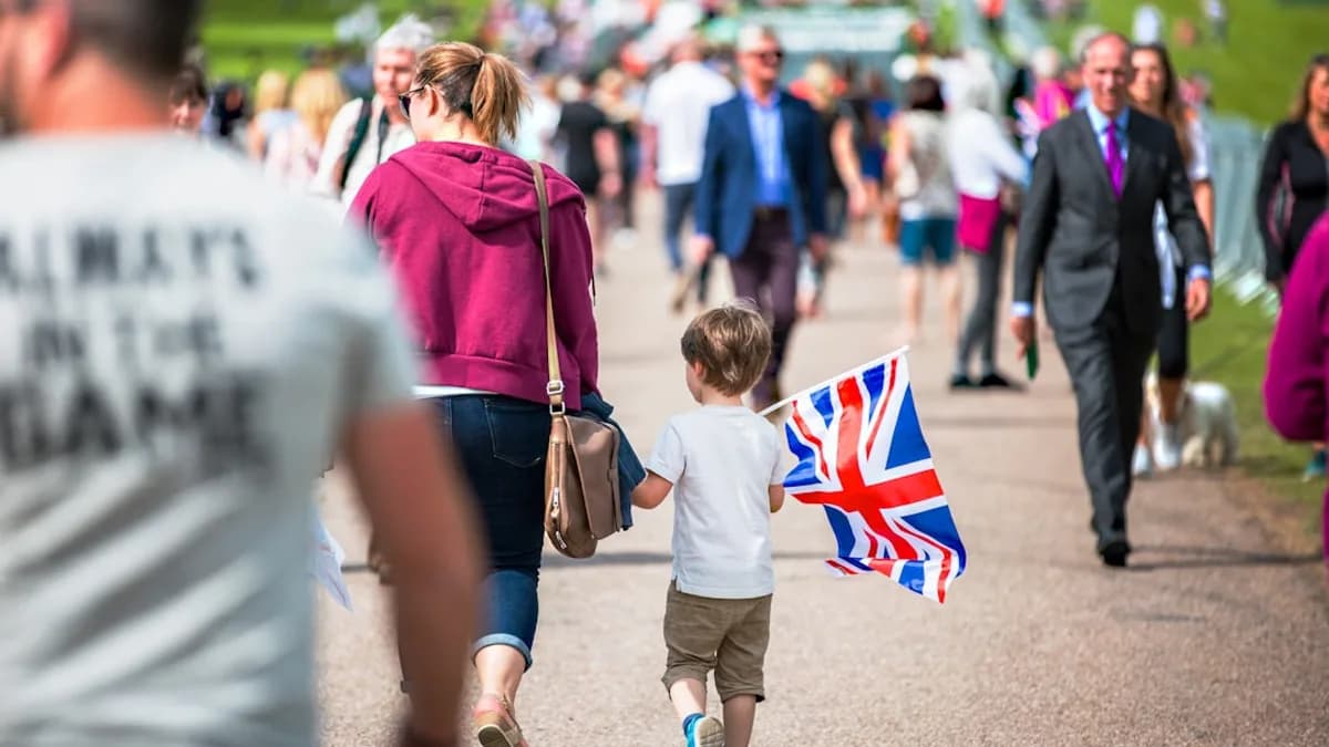 selective focus photography of boy holding U.K. flag walking on pathway full of people