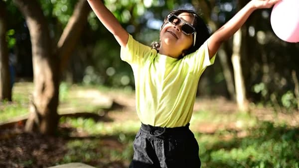 Young girl with arms raised in a park