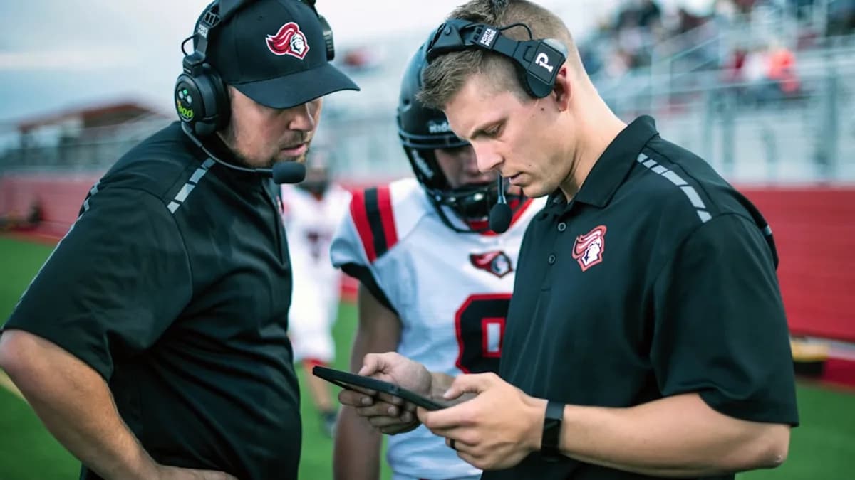 man in black and white uniform holding black smartphone