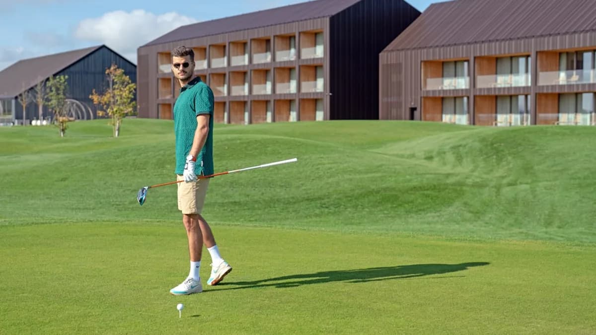 a man walking across a lush green golf course