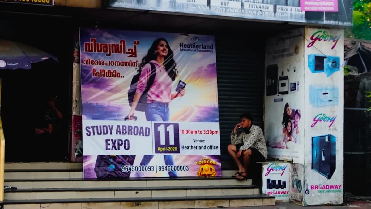 Man sitting near a large "study abroad expo" advertisement.