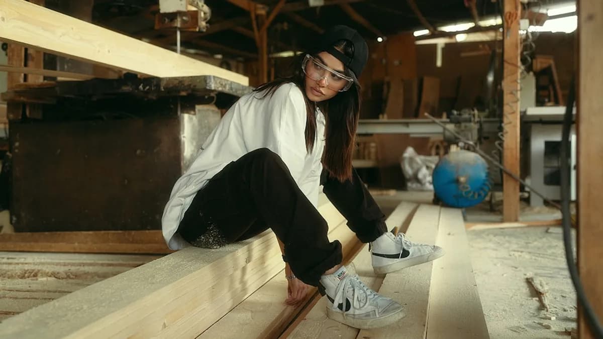 Young woman sitting on lumber in workshop