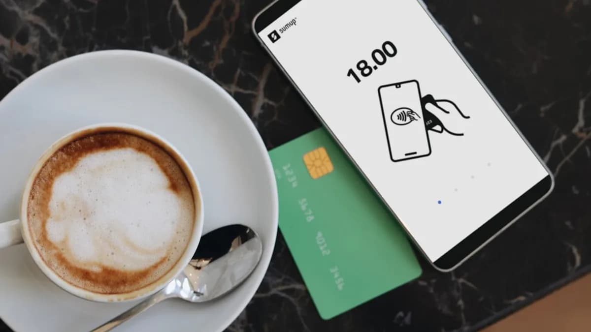 A cup of coffee on a saucer next to a credit card